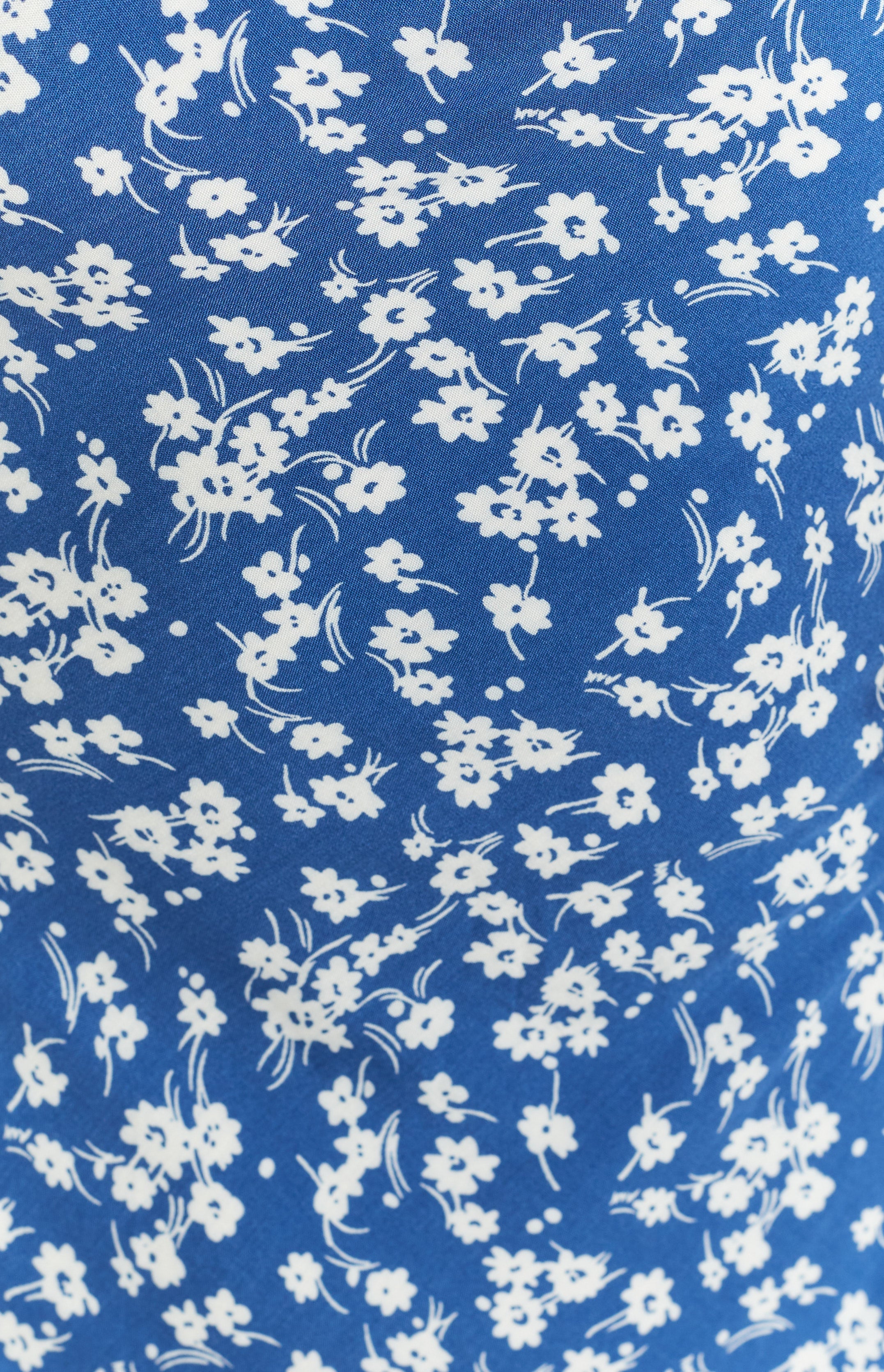 Close-up of the blue fabric with delicate white floral print on the midi dress