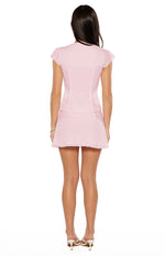 Rear view of a pink woven mini skirt with a subtle A-line silhouette and a ruffled hem