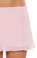 Close-up of the light pink woven mini skirt fabric with a subtle texture and a delicate ruffled hem
