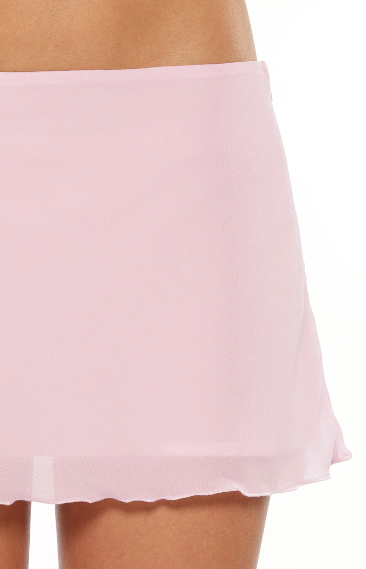 Close-up of the light pink woven mini skirt fabric with a subtle texture and a delicate ruffled hem