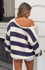 Rear view of a navy and white striped chunky knit sweater with a wide off-shoulder neckline and thick knit texture