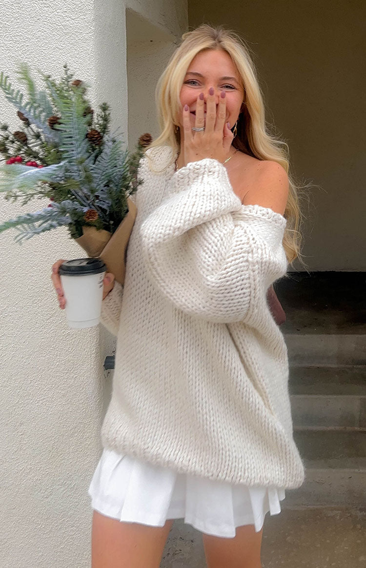 Off-the-shoulder cream chunky knit sweater with a wide neckline and voluminous long sleeves