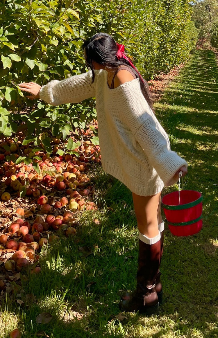 Side view of an oversized cream chunky knit sweater with an off-shoulder neckline and long sleeves