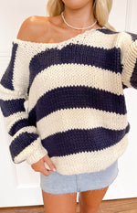 Close-up of the off-shoulder neckline and chunky knit texture of the navy and cream striped sweater
