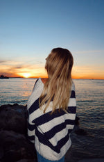 Back view of a navy and white striped chunky knit sweater with thick horizontal stripes and a relaxed fit