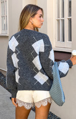 Rear-side view of a grey argyle print oversized cardigan with white diamonds and a fuzzy knit texture