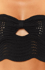 Close-up of the black knit top with a bow detail and keyhole cutout at the bust