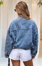 Rear view of an oversized mid wash denim jacket with all-over pearl embellishments