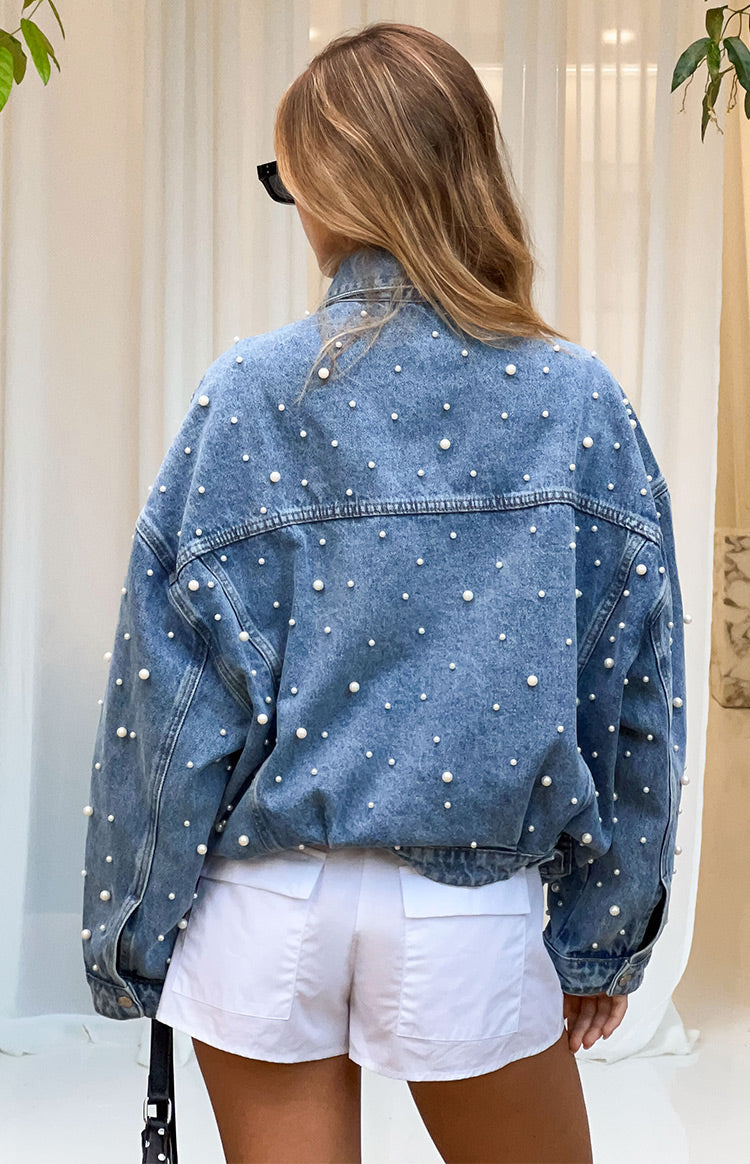 Rear view of an oversized mid wash denim jacket with all-over pearl embellishments