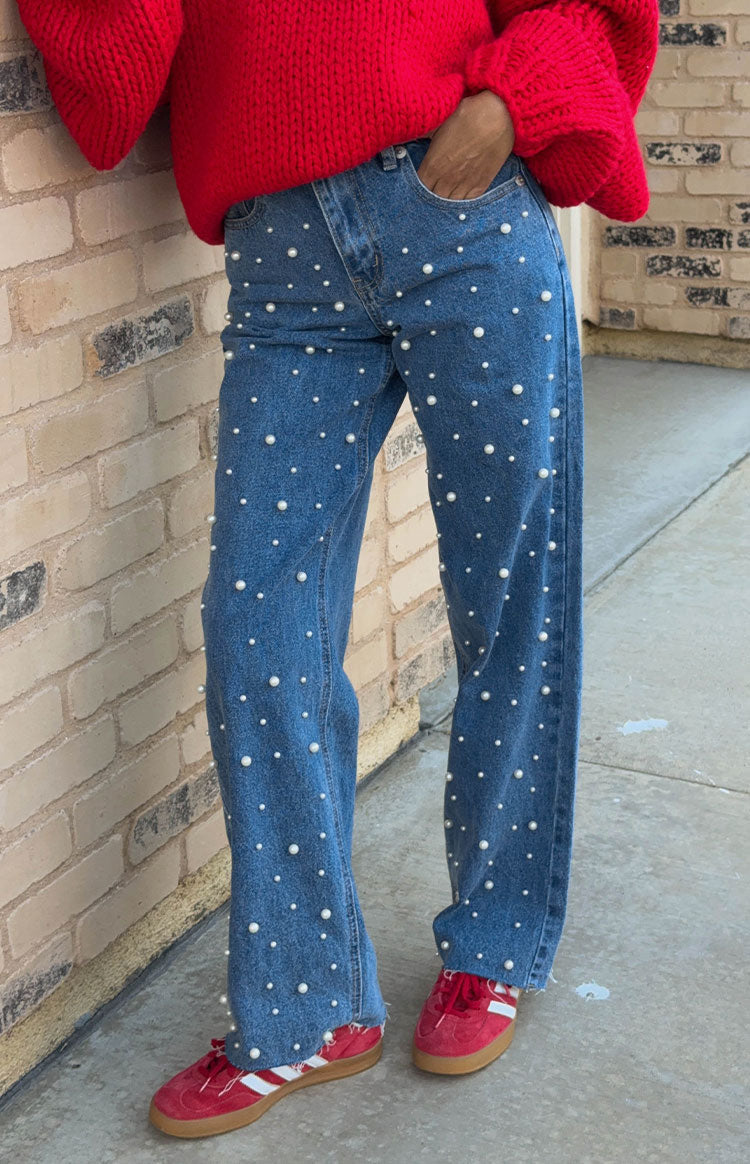 Mid wash high waisted jeans with all-over pearl embellishments and a frayed hem