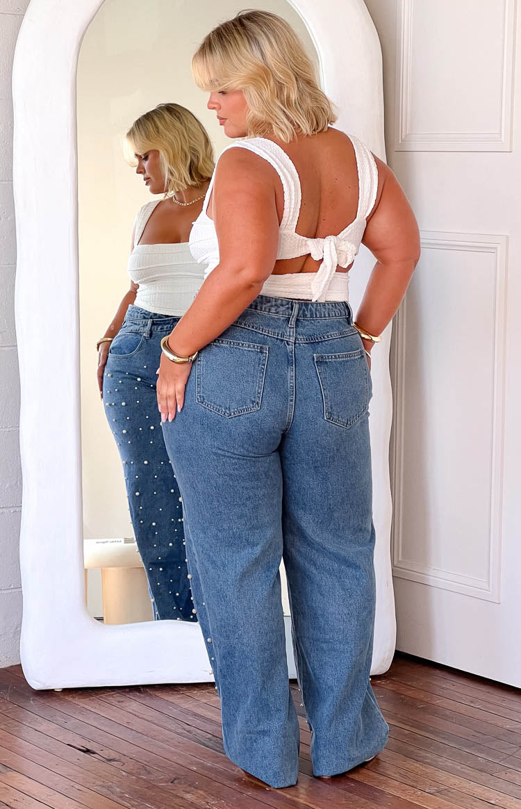 Mid wash high waisted jeans with all-over pearl embellishments and a frayed hem