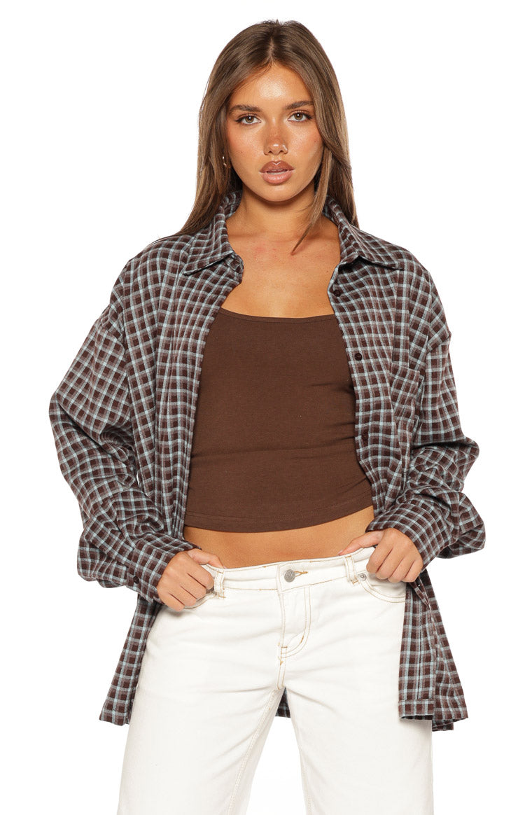 Front view of an oversized brown plaid long sleeve shirt with light blue lines, worn open to show the collared neckline