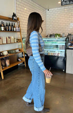 Side view of a blue and white striped knit sweater with long sleeves and a cropped, fitted silhouette