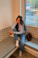 Front view of a blue and white horizontal stripe knit sweater with a partial zip front and long sleeves