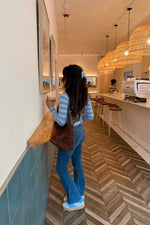 Rear view of a long sleeve knit sweater with alternating light blue and white horizontal stripes