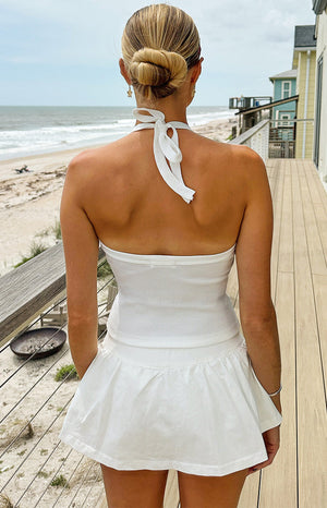 Rear view of a white micro skort with a gathered waist and flared hem