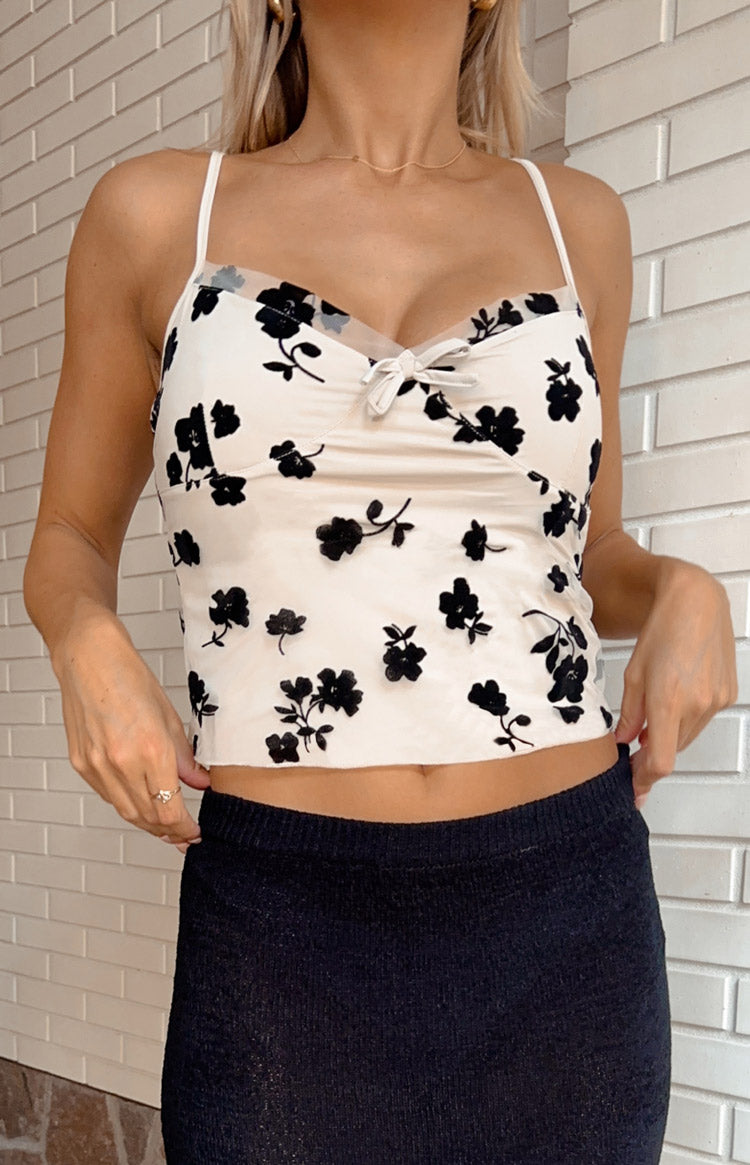 Close-up of the beige mesh top with black floral pattern, sweetheart neckline, and small white bow