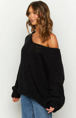 Oversized black chunky knit sweater with a wide neckline worn off one shoulder, highlighting the textured knit