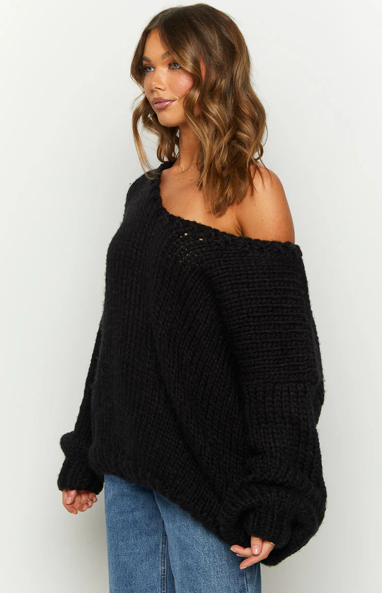 Oversized black chunky knit sweater with a wide neckline worn off one shoulder, highlighting the textured knit