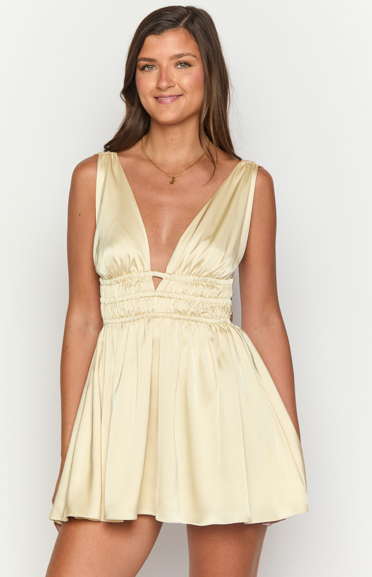 Close-up of the deep V-neck and triangular cutout on a yellow satin mini dress with shirred waist