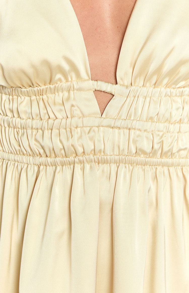 Close-up of the yellow dress showing the shirred elasticated waist and triangular cutout at the deep V-neck