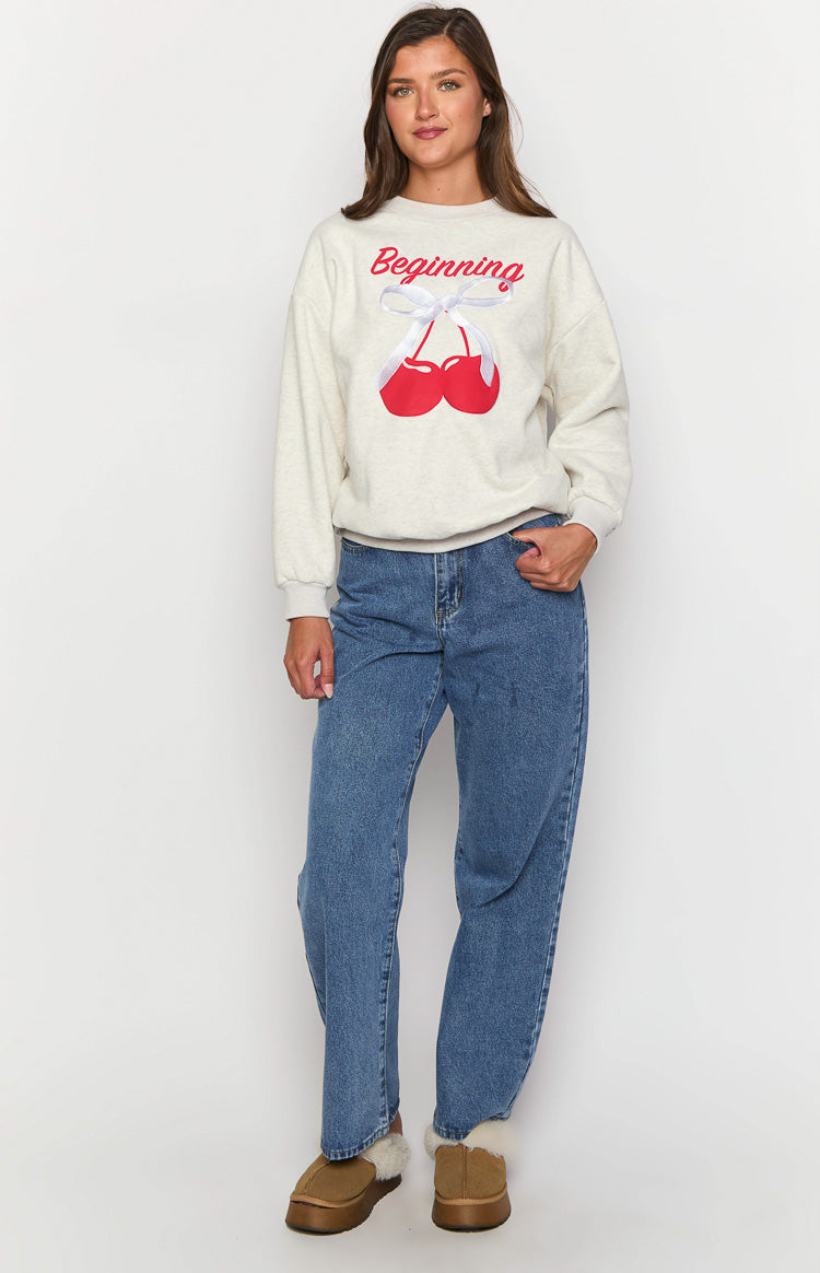 Oat marle crew neck sweater with a large red cherry graphic, showing the relaxed fit, ribbed cuffs, and hem