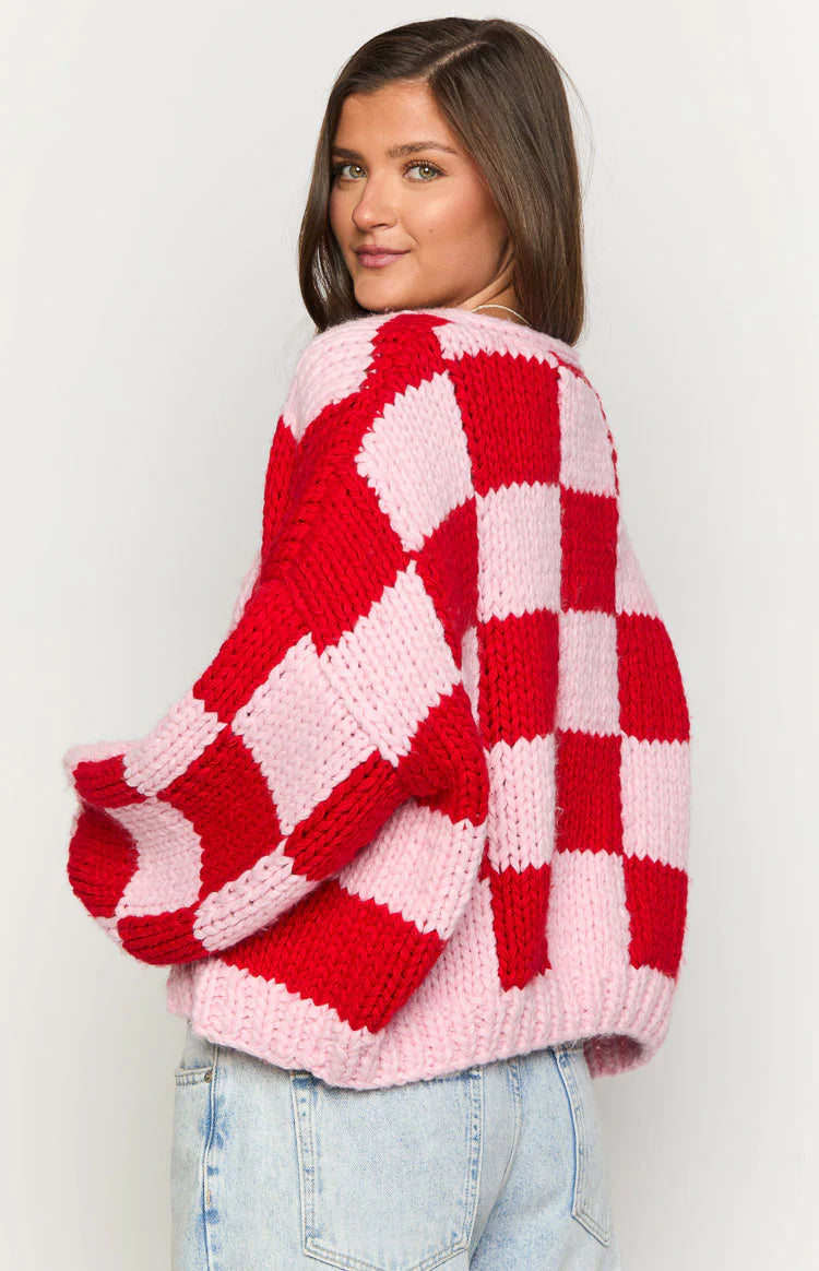 Top-down view of a pink and red checkered chunky knit cardigan with long sleeves