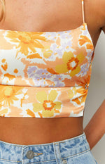 Close-up of the side ruching with silver O-rings on the white, orange, and lilac floral crop top