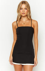 Front view of a black mini dress with a square neckline, thin spaghetti straps, and a white pleated hem