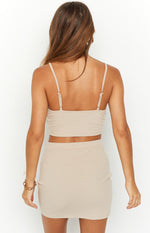 Rear view of a beige ribbed cropped singlet top with thin adjustable spaghetti straps