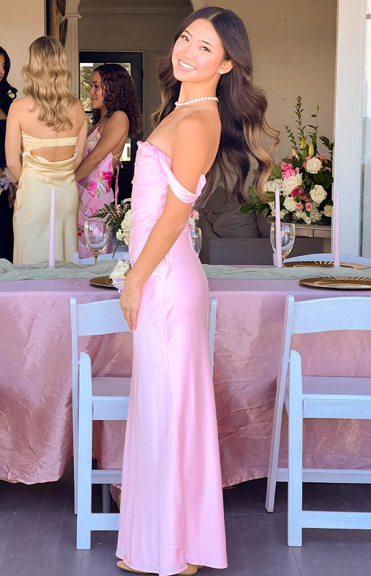 Side view of the light pink off-shoulder maxi dress showing the fitted bodice and flowing skirt