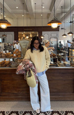 Full length view of a butter yellow button-down cardigan with a crew neck, relaxed fit, and ribbed hem