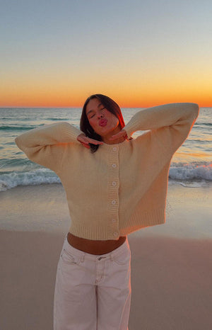 Front view of a butter yellow cropped button-down cardigan with round buttons, long sleeves, and ribbed hem
