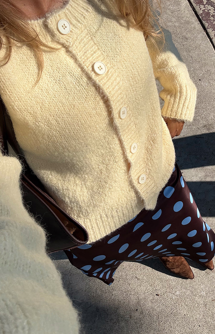 Close-up of a butter yellow fuzzy knit cardigan with white buttons and ribbed cuffs