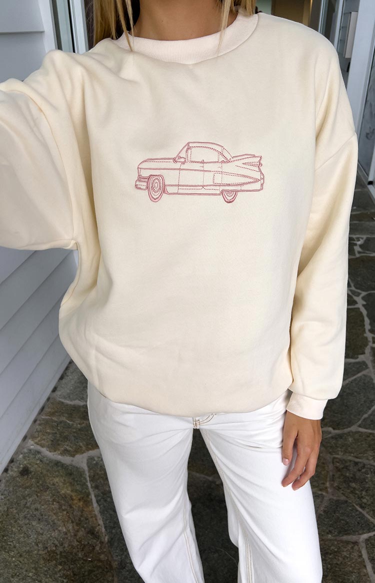 Front view of a cream crew neck sweater with a pink embroidered vintage car graphic
