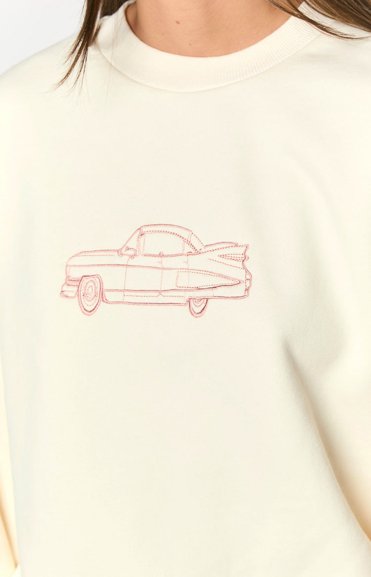 Close-up of the cream crew neck sweater featuring a red embroidered vintage car design