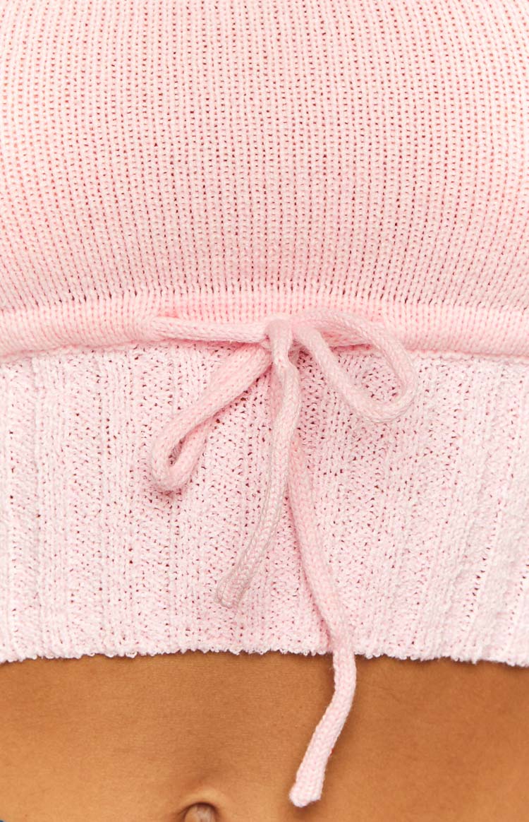 Close-up of the pink knit tube top's drawstring detail tied in a bow with varied knit textures