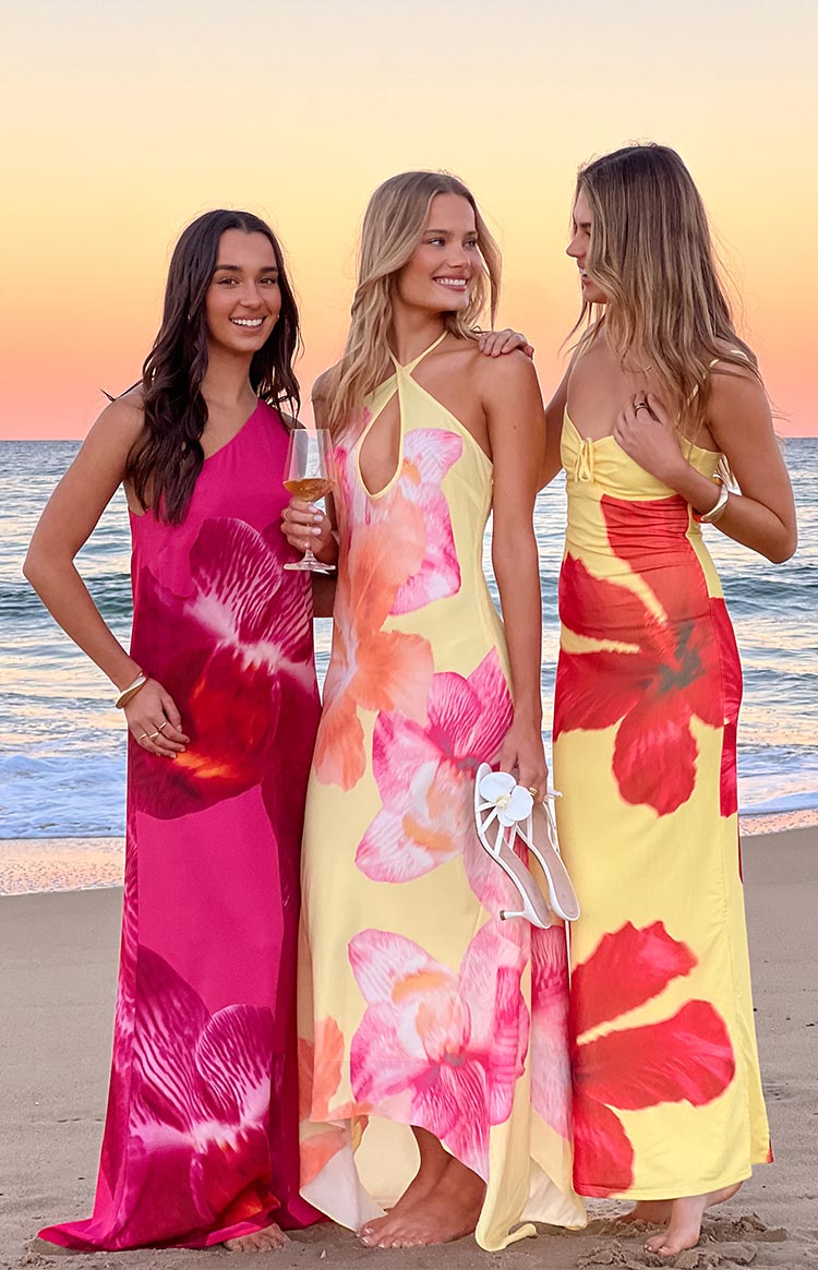 Front view of a yellow hibiscus floral halter maxi dress with a keyhole cutout and flowy hem