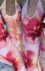 Close-up of two halter maxi dresses with scoop necklines, showing vibrant pink and orange floral prints on yellow and light p