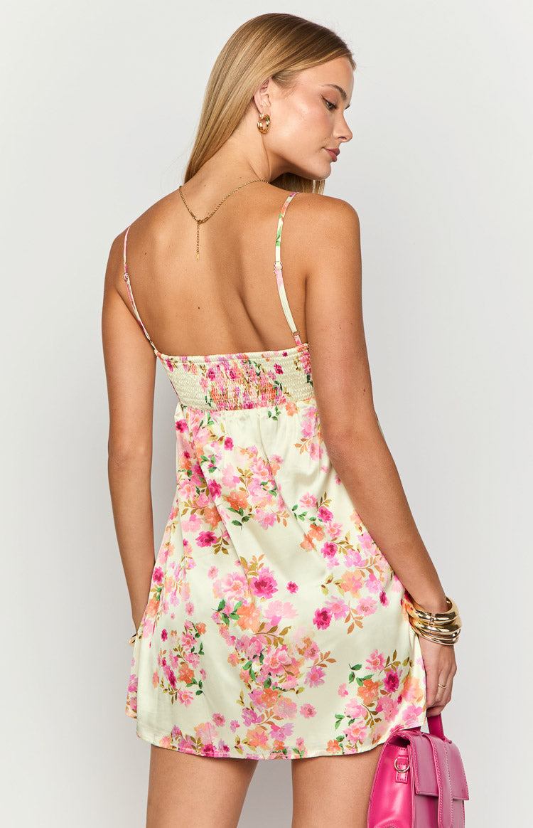 Rear view of a yellow satin mini dress with a smocked back panel and delicate spaghetti straps, adorned with a pink and orange floral pattern