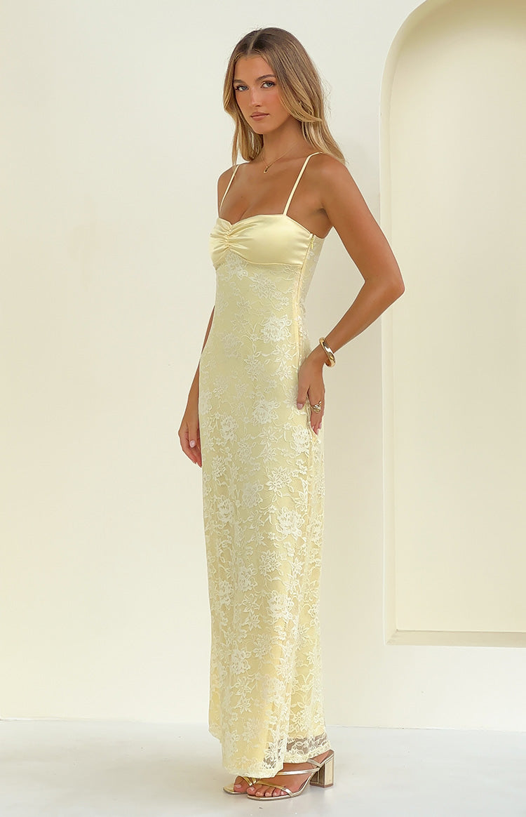 Side view of a yellow maxi dress featuring a ruched bust, thin spaghetti straps, and a floral lace overlay