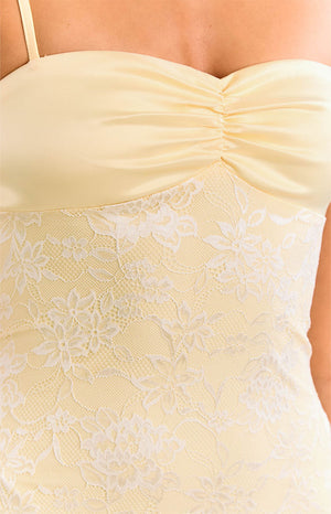 A model in a yellow lace maxi dress with a sweetheart neckline and thin straps. This gorgeous formal gown features a sheer lace fabric over a yellow lining. An amazing dress for prom or a wedding guest.