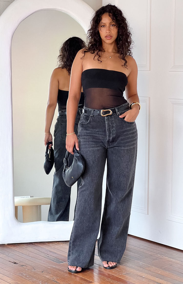 Full length view of washed black straight leg jeans with a high waist, visible button fly, and frayed hem