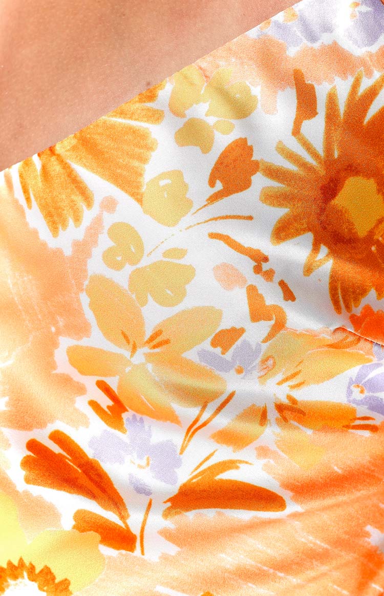 Close-up of the white fabric with an orange, yellow, and light purple brushstroke floral print on the maxi dress
