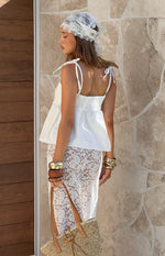 Side view of a white top with shirred back panel and adjustable tie shoulder straps