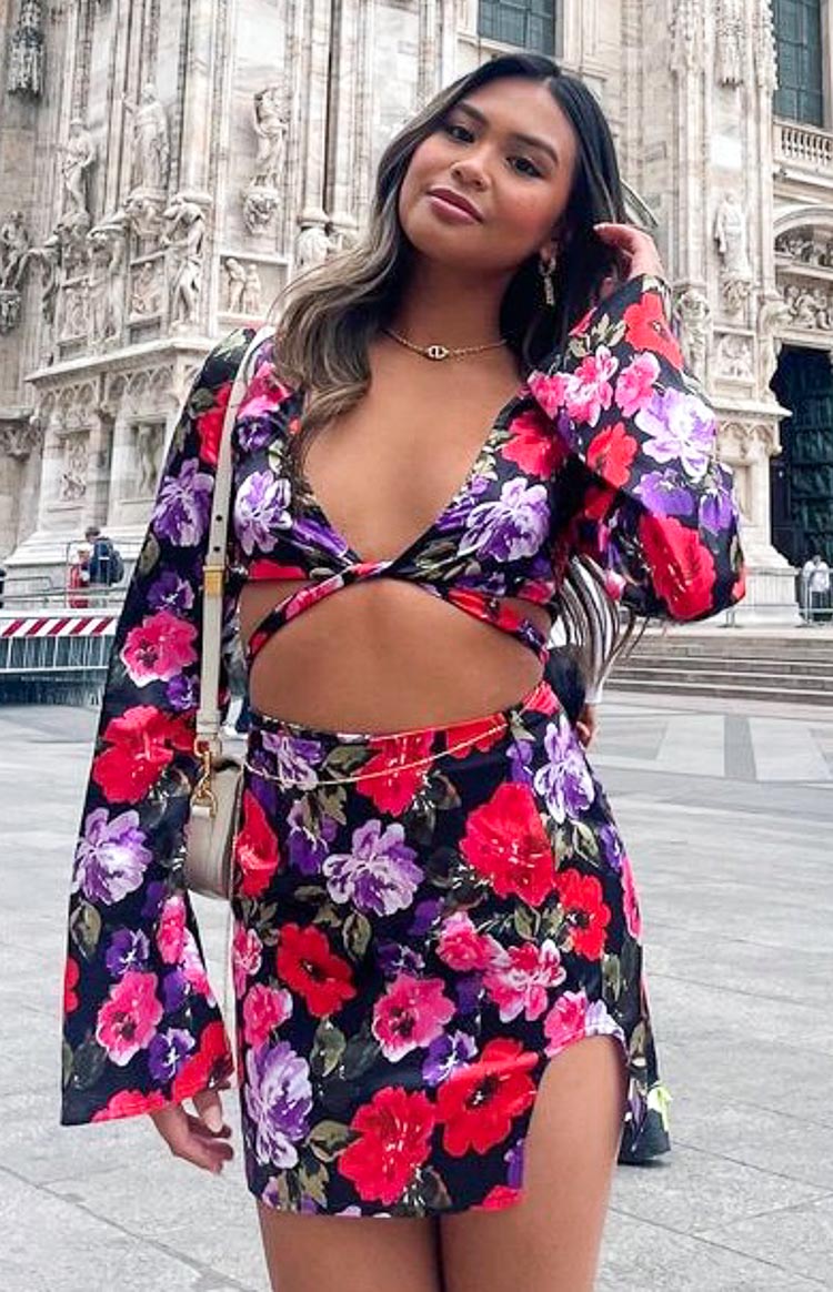 Black floral print wrap top with deep V-neck, twisted front, waist cutouts, and long flared sleeves