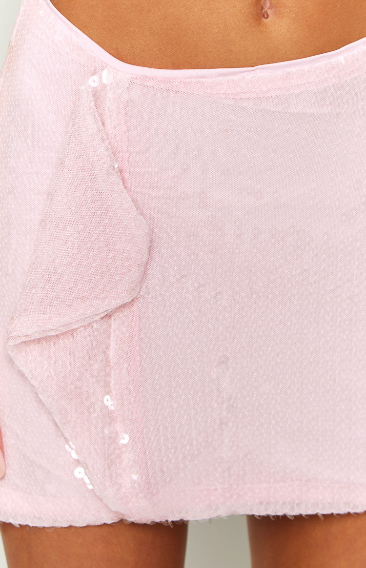 Close-up of the pink sequin fabric and wrap-style front detail of a mini skirt