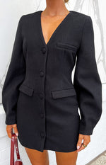Close-up of the black blazer mini dress showing the V-neck, button-front, and faux flap pockets