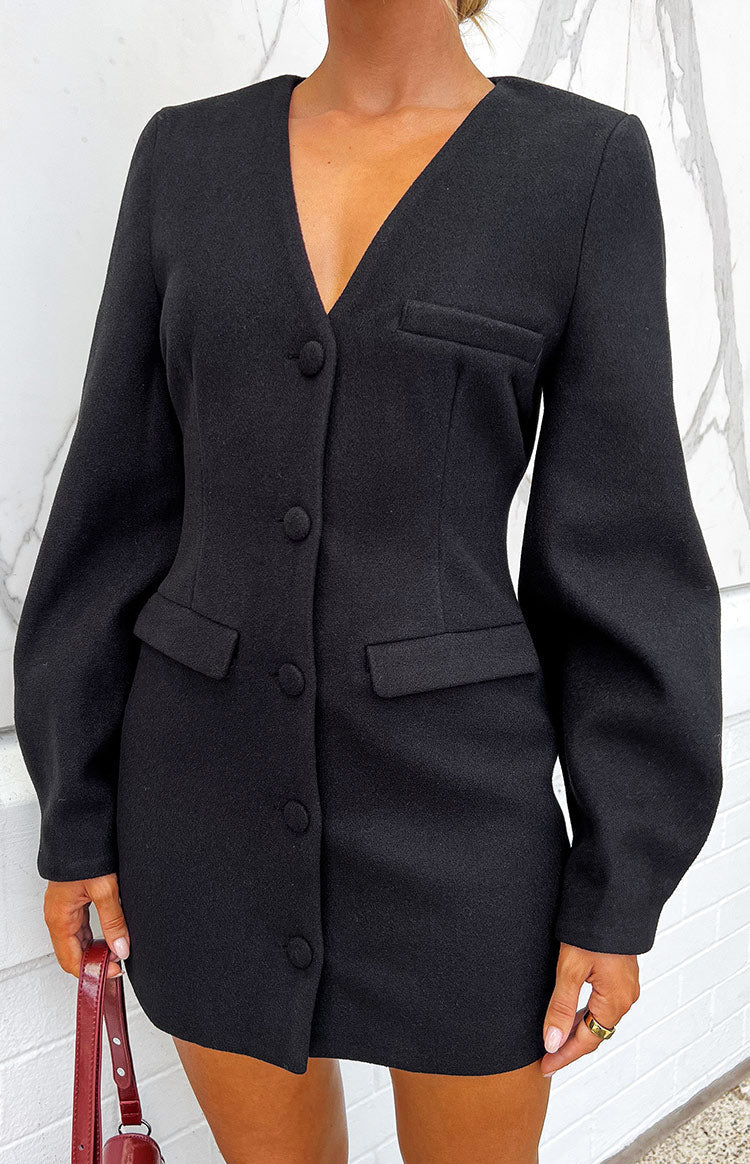 Close-up of the black blazer mini dress showing the V-neck, button-front, and faux flap pockets
