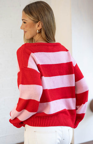 Rear view of the red and pink striped knit sweater with a wide boat neckline and ribbed hem